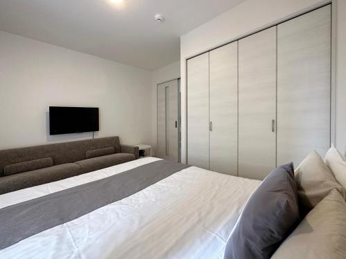a bedroom with a bed and a tv on the wall at Yutori by b hotel - Good Apartment for 3 people with free wifi in Onomichi