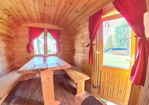 einen Holztisch in einer Holzhütte mit einem Fenster in der Unterkunft Rheingau 524 Schlaffassdorf direkt am Rhein in Geisenheim