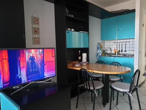 cocina con mesa con sillas y TV en Residence le Dune en Lido di Camaiore