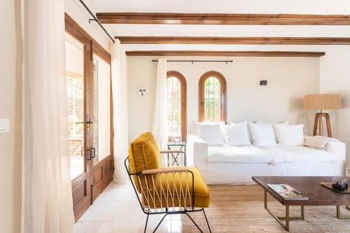a living room with a white bed and a yellow chair at Casa Nunca Javea: geniet van het uitzicht in Jávea