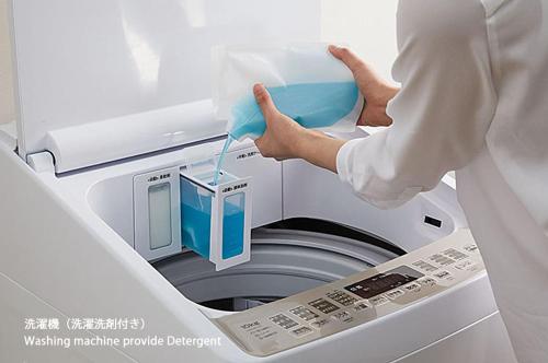 eine Person steckt etwas in eine Waschmaschine in der Unterkunft bHOTEL Yutori - 1Br Apartment in Onomichi City near the Station in Onomichi