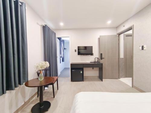a bedroom with a bed and a desk and a television at G Hotel Sai Gon in Ho Chi Minh City