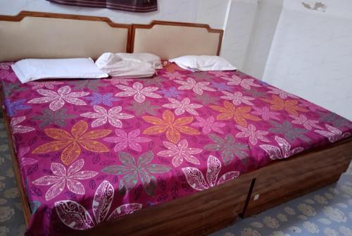 uma cama com uma colcha roxa com flores em GRG Kameshwar Bhawan Rajgir em Rajgir