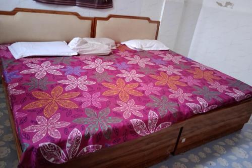 a bed with a purple bedspread with flowers on it at GRG Kameshwar Bhawan Rajgir in Rājgīr