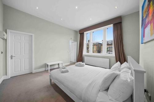 - une chambre avec un grand lit blanc et une fenêtre dans l'établissement Queen’s Park, Spacious 3 Bedroom Flat, à Londres