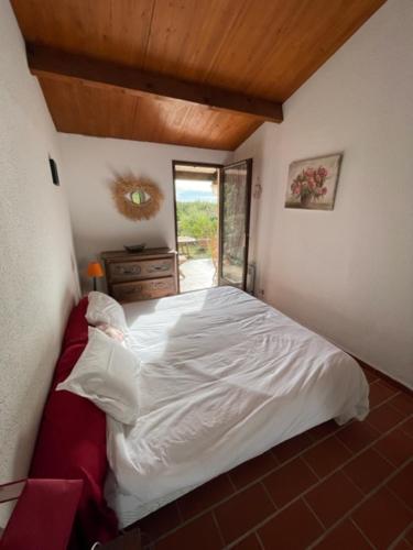 une chambre avec un lit blanc et une fenêtre dans l'établissement La petite maison sur la colline - Piscine privée, à La Londe-les-Maures