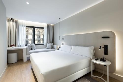 a white bedroom with a large bed and a couch at Royal Ramblas in Barcelona