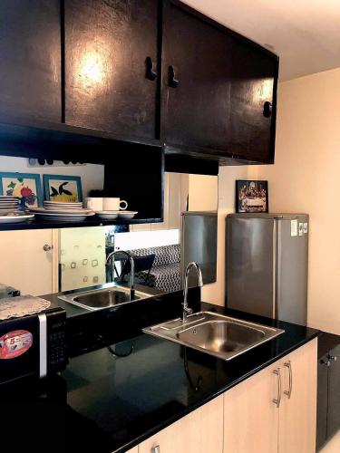 a kitchen with two sinks and stainless steel appliances at JT Tagaytay Suites in Tagaytay