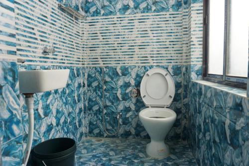 TAJ HERITAGE Hotel And Restaurant -call 94353-5O876 في جورهات: حمام من البلاط الأزرق مع مرحاض ومغسلة