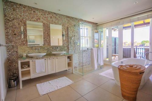 bagno con 2 lavandini, vasca e doccia di Eden Island Luxury Ocean Front Villa with Pool a Victoria