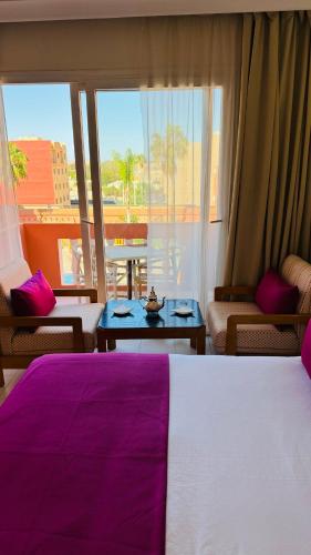 a bedroom with a large bed with a purple blanket at Hotel Idou Tiznit in Tiznit
