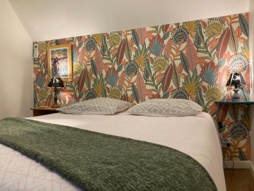1 cama con 2 almohadas en un dormitorio con papel pintado en Chambre d'hôtes sur le chemin de la Loire à vélo en Les Ponts-de-Cé