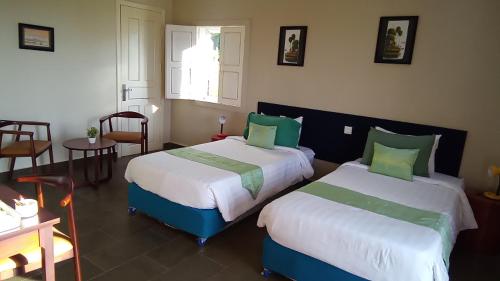 Un dormitorio con dos camas y una mesa y sillas. en Koh Ker Hotel and Restaurant, en Phumĭ Mréch