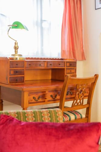 a desk with a lamp and a chair in a room at Gästehaus Englischer Garten in Munich