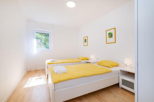 a white bedroom with a bed with yellow sheets at Infinity Dalmatia Apartments in Vinjerac