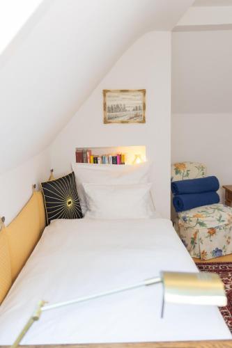 a bedroom with a white bed and a chair at Gästehaus Englischer Garten in Munich