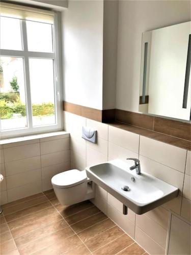 a bathroom with a sink and a toilet and a mirror at Wohnen auf Zeit Wohnung 05 in Jüterbog