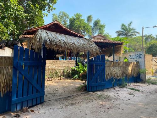 a house with a blue gate and a thatched roof at Suíte BOTOS DE ALTER in Alter do Chao