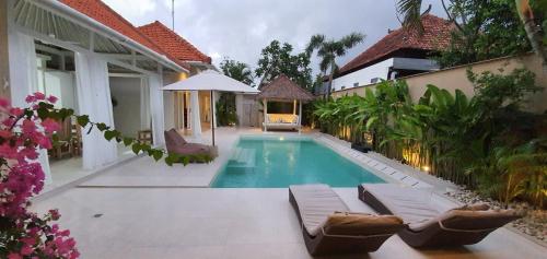 a swimming pool with lounge chairs and a house at La Dolce Villa in Seminyak