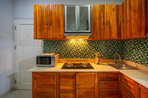 a kitchen with wooden cabinets and a microwave on a stove at iVilla in Jimbaran