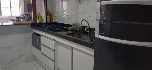 a kitchen with a sink and a black refrigerator at No coração de Boa Viagem in Recife