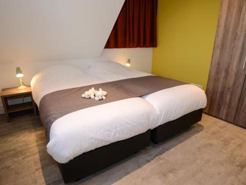 Un dormitorio con una cama grande con dos animales de peluche. en Duinbraam, en Den Burg