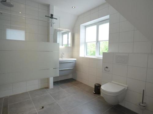 Un baño con inodoro, lavabo y ventana. en Duinbraam, en Den Burg