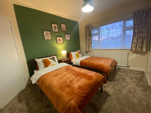two beds in a room with a green wall at Oadby Town Mid-Century Bungalow in Oadby