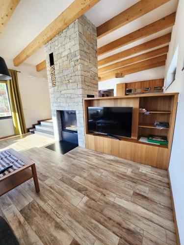 a living room with a large television and a stone fireplace at Vila Stašov in Polička