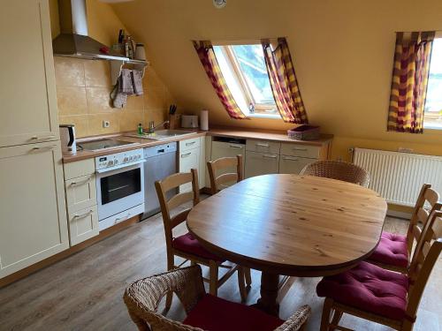 a kitchen with a wooden table and chairs in it at Haus Wildgans - Ferienwohnung Sonnenblume in Behrensdorf
