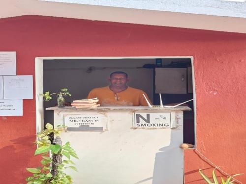 een man bij een raam in een gebouw bij LEON HOME STAY in Bogmalo