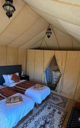 a bedroom with two beds in a tent at Erg Chebbi Luxury Camp in Merzouga