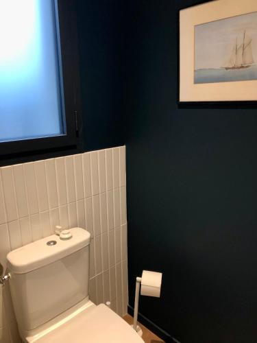 a bathroom with a toilet and a picture of a boat on the wall at Villa Tidinghi, plage de Rospico à pied in Névez