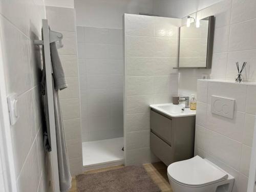 a white bathroom with a toilet and a sink at Très bel appartement neuf - Parking et Terrasse in Biscarrosse