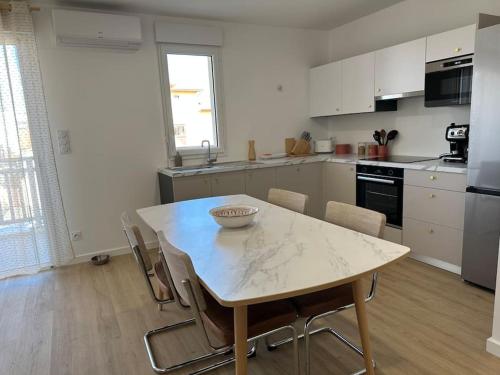 une cuisine avec une table et des chaises dans une pièce dans l'établissement Très bel appartement neuf - Parking et Terrasse, à Biscarrosse