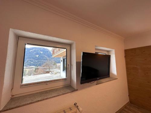 a flat screen tv in a room with a window at DAS MANFRED in Sankt Michael im Lungau