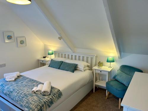 una camera da letto con un letto bianco e una sedia blu di Fowey River Views a Fowey