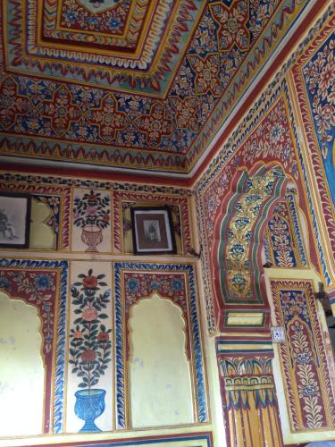 a room with a colorful ceiling with paintings on it at Narayan Niwas Castle in Rāmgarh