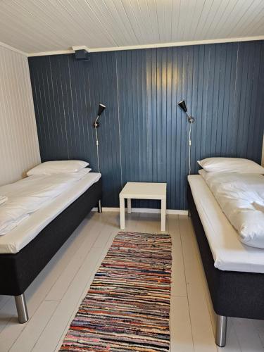 two beds in a room with a table and two lamps at Å Rorbuer - by Classic Norway Hotels in Å