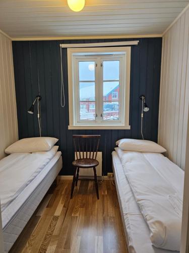 two beds in a room with a chair and a window at Å Rorbuer - by Classic Norway Hotels in Å