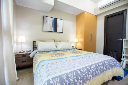 a bedroom with a bed with a blue and white bedspread at Cozy 1BR with Balcony and Netflix in Uptown BGC in Manila