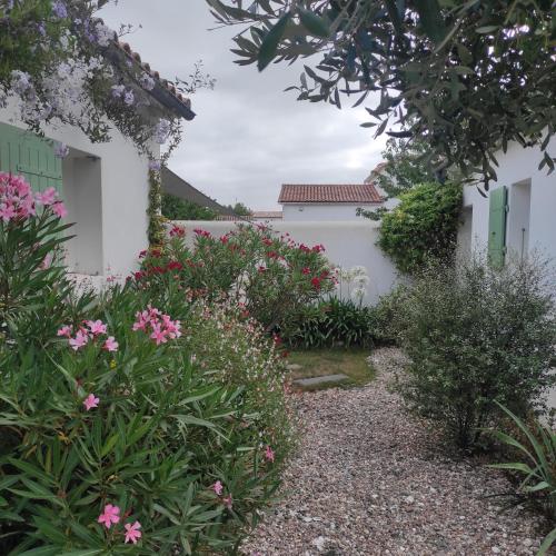 a garden with pink flowers in front of a white fence at Maison 3 chambres plus 1 studio indépendant in Sainte-Marie-de-Ré