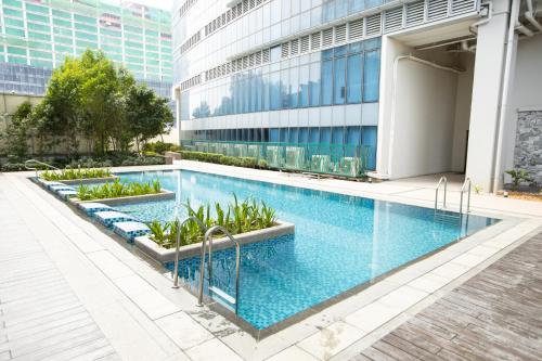a swimming pool in front of a building at Cozy 1BR with Balcony and Netflix in Uptown BGC in Manila