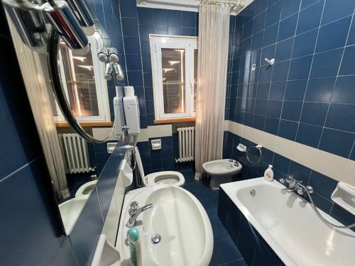Baño de azulejos azules con aseo y lavamanos en Casa Mattioli, en Mombaroccio