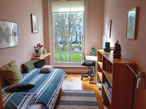 1 dormitorio con cama, ventana y escritorio en Stunning property overlooking local park, en Londres
