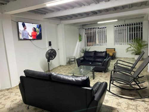 uma sala de estar com mobiliário de couro preto e uma televisão de ecrã plano em Hotel CAB DE TOLU em Tolú