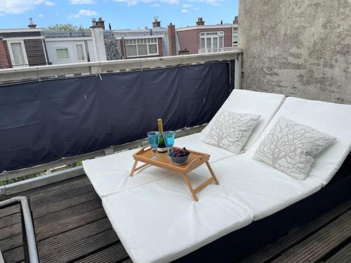 un sofá blanco en un balcón con mesa en Luxurious top apartment near beach, musea & Keukenhof en The Hague