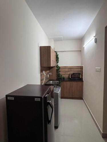 a kitchen with a black refrigerator and wooden cabinets at Airport Freshups Cochin in Nedumbassery