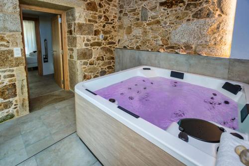 a bath tub filled with purple water in a bathroom at A de Lucía in Muxia