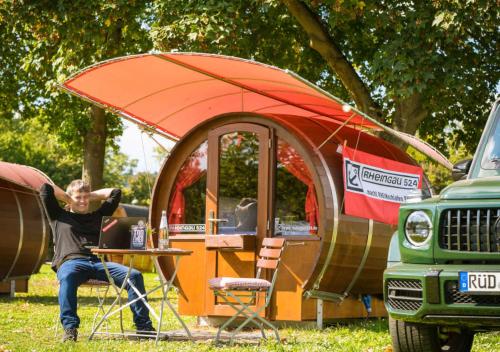 a man sitting at a table in front of a tent at Rheingau 524 Schlaffassdorf direkt am Rhein in Geisenheim